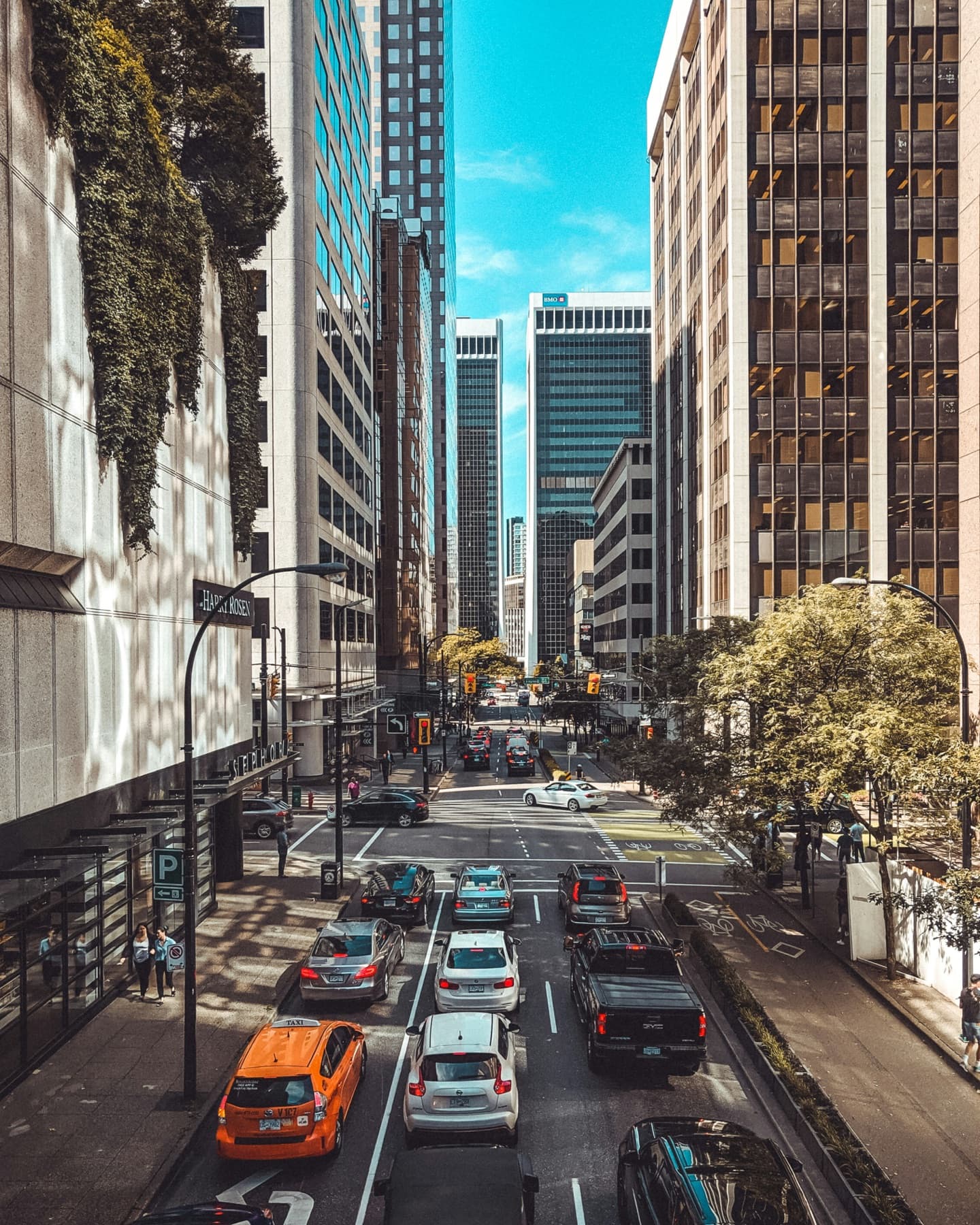 A downtown Vancouver street lined with office towers, busy with traffic under a blue sky